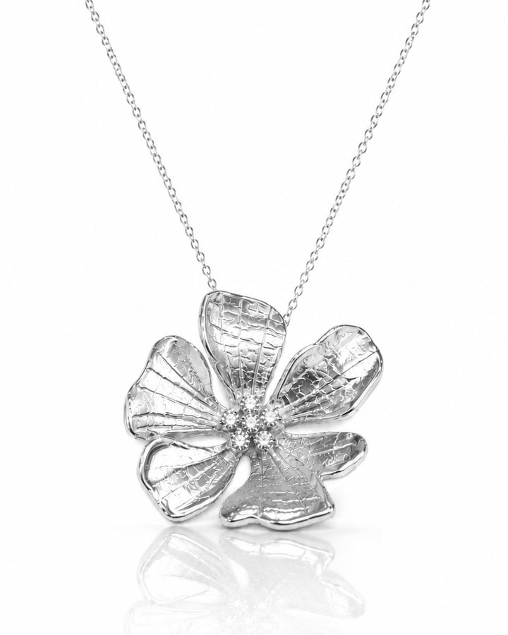 Textured hibiscus flower pendant with a stone centre on a fine silver chain, on white