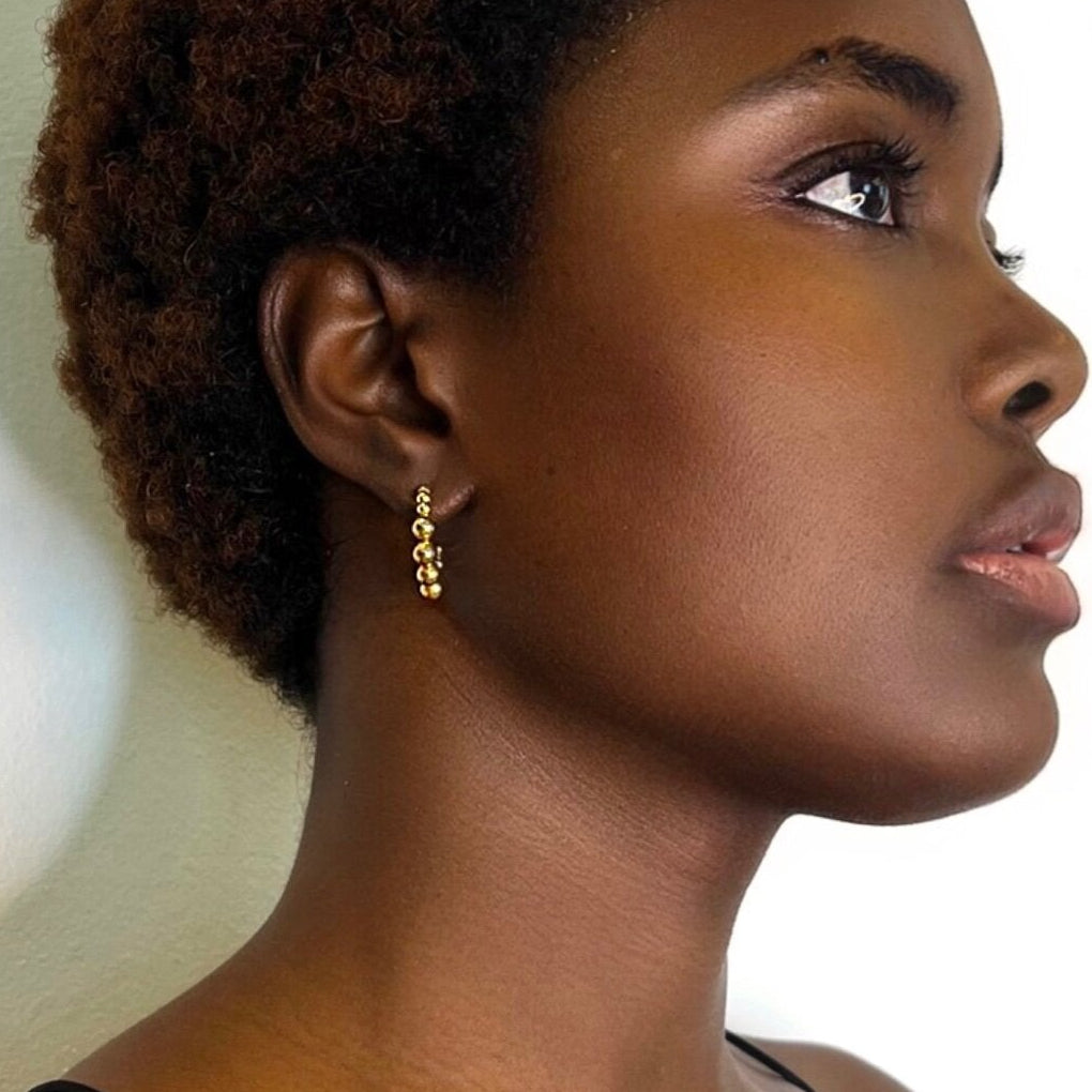 Graduated gold bead hoop worn at the ear, seen in profile