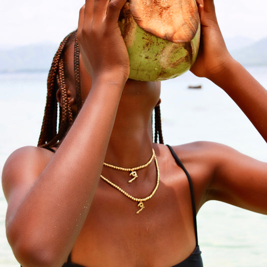 Gold bead chokers with Ayiti charms worn at the shore, saltwater-safe 14K gold PVD