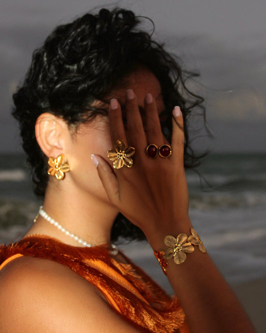 Gold flower earrings, ring and bracelet worn together at the shore on a Caribbean trip