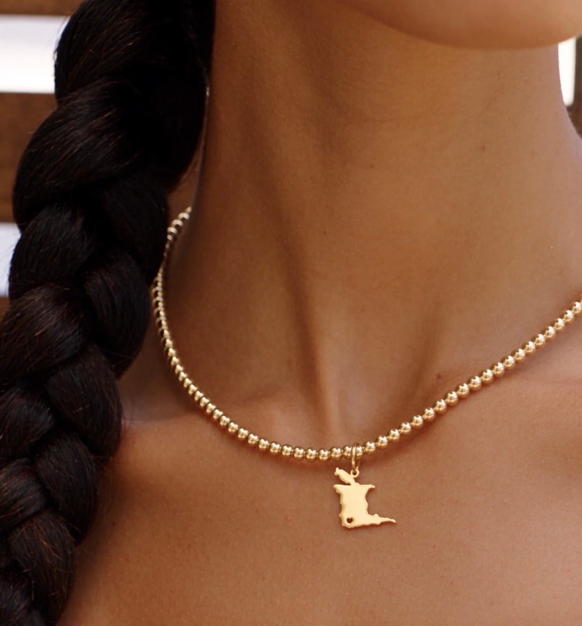 Trinidad map charm on a gold bead choker worn close at the neckline