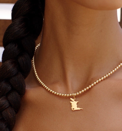 Trinidad map charm on a gold bead choker worn close at the neckline