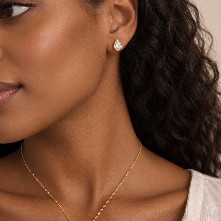 Bezel-set pear stud at the ear, worn with the matching drop necklace