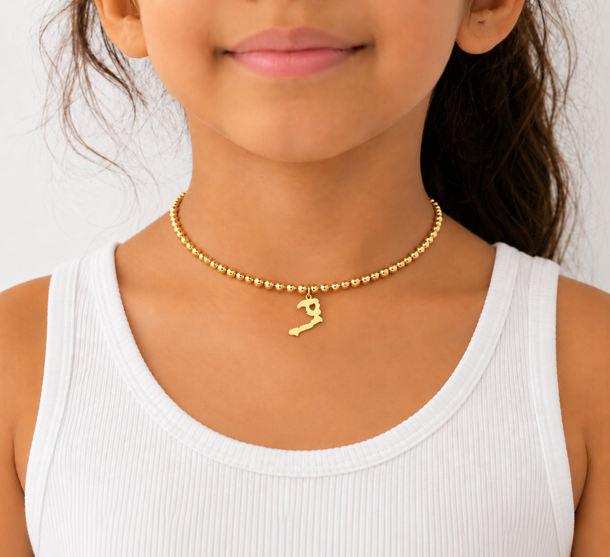 Ayiti map charm on a fine gold bead choker, worn at the neckline with a white tank