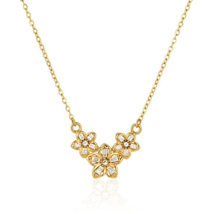 Three crystal-set flowers clustered on a fine gold chain, laid flat on white