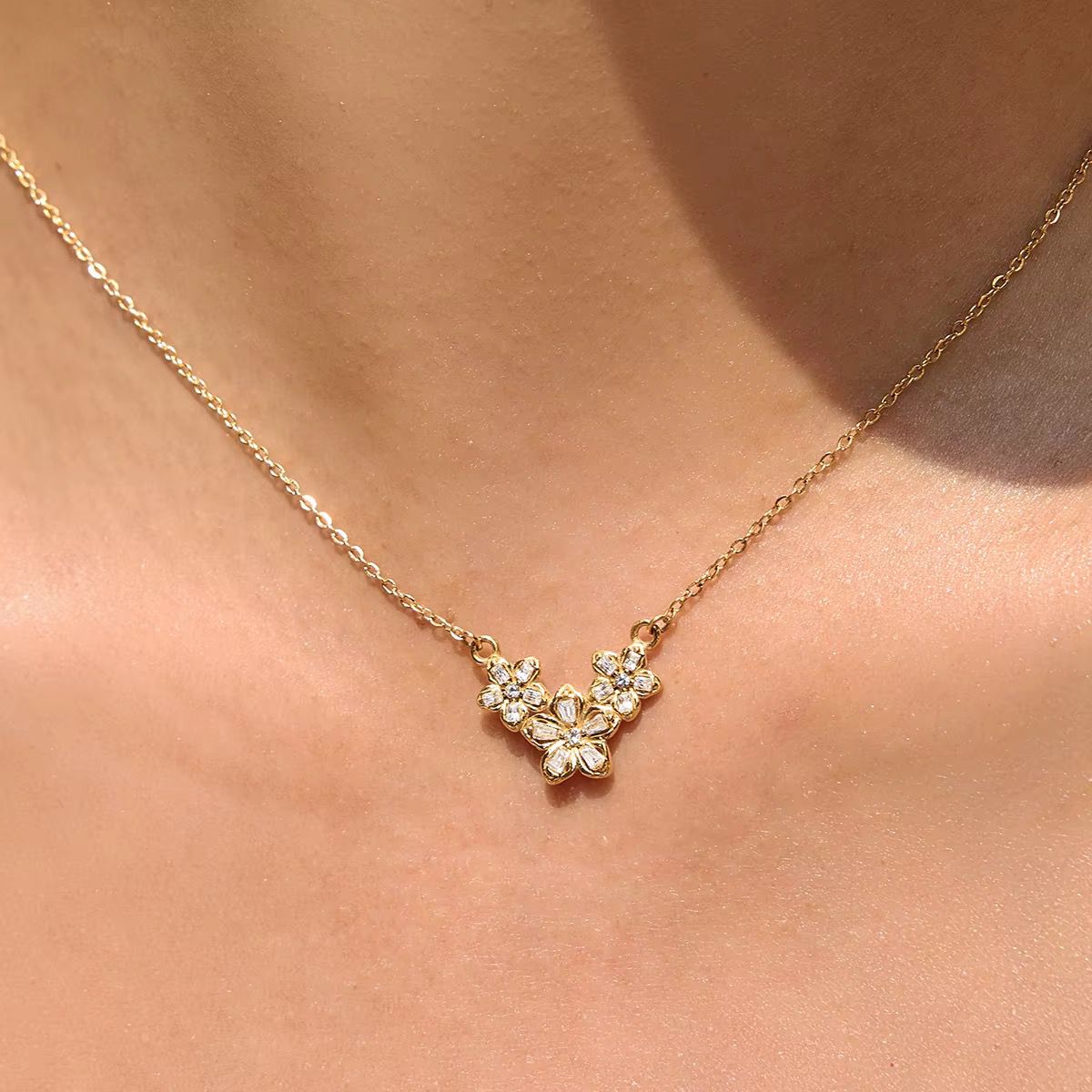 Gold flower cluster necklace sitting just below the collarbone